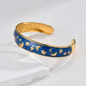 Bracelet jonc étoilé et lune plaqué or avec émail bleu et cristaux sur support blanc