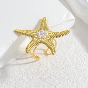 Golden starfish ring with white pearls and adjustable band on white stone background