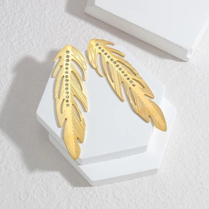 Golden feather earrings with sparkling rhinestones on a minimalist white display