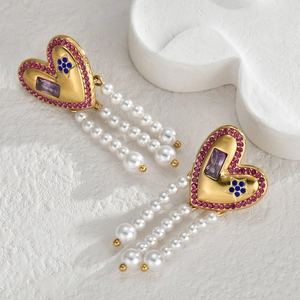 Détail de boucles d'oreilles cœur doré avec cristaux violets et glands de perles