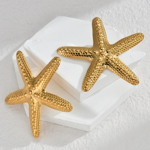 Golden starfish stud earrings with textured metallic surface on white stone pedestals