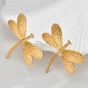French retro dragonfly gold earrings with hammered texture on a white shell tray