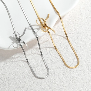 Minimalist gold and silver snake chain necklaces with bow knot design on white tray