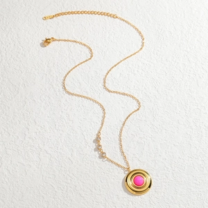 Détail du collier doré avec pendentif rond rose et trois accents étincelants en zircon