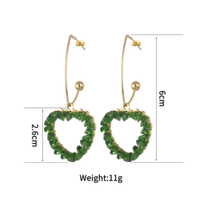 Détail de boucles d'oreilles cœur en cristal vert avec crochets dorés de 6 cm de long