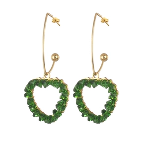 Boucles d'oreilles cœur dorées avec perles de cristal vert facetté sur fond blanc