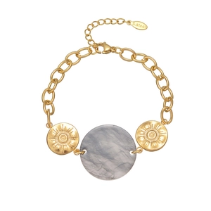 Close-up of golden stainless steel bracelet with marble charm and sunburst charms