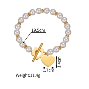 Détail du pendentif cœur et fermoir fleur sur un bracelet de perles blanches