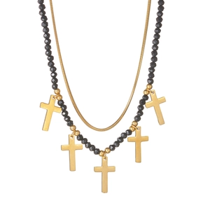 Close-up of double-layer necklace with gold snake chain and black beads with cross charms