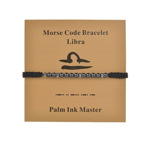 Macro detail of Libra Morse code beaded bracelet on kraft display card with black cord
