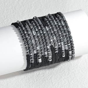 Minimalist black braided zodiac bead bracelet set on a white cylindrical display stand