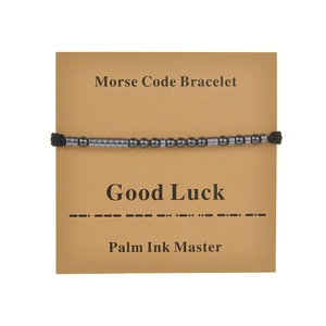 Detail of Morse code bracelet featuring dark beads and Good Luck gift card on white background