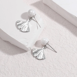 Elegant gingko leaf pearl earrings in silver finish on minimalist stone display