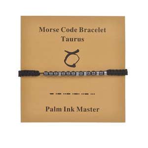 Taurus morse code bracelet with black obsidian beads and woven cord on display card