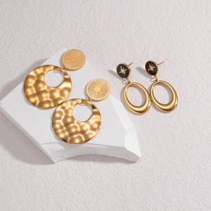 Vintage hollow gold drop earrings with sunburst and star patterns on stone display