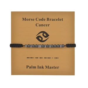 Cancer Morse Code bracelet with dark beads and metal tubes on display card