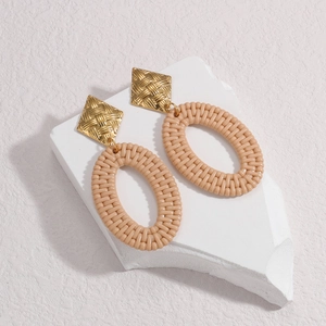 Bohemian ethnic style woven hoop earrings with golden square studs on a stone pedestal