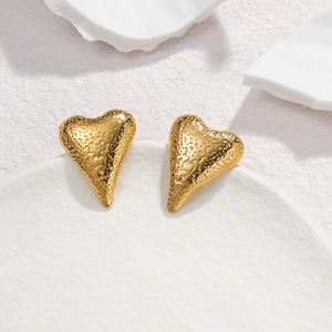 Textured hammered heart stud earrings in gold stainless steel on elegant stone background