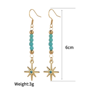 Dettaglio orecchini pendenti boho da 6 cm con perle turchesi e ciondolo a stella oro