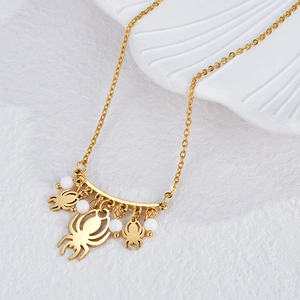 Elegant 18k gold chain necklace with spider charms and white beads on a shell display