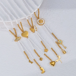 Colliers pendentifs coeur avec perles et billes dorées sur un plat en porcelaine blanche