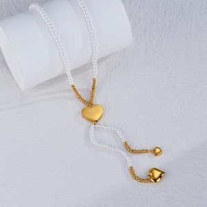 Collier en Y élégant avec perles blanches et pendentifs cœur doré sur pilier blanc
