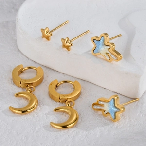 Chic gold celestial earring set with star and moon charms on white stone surface
