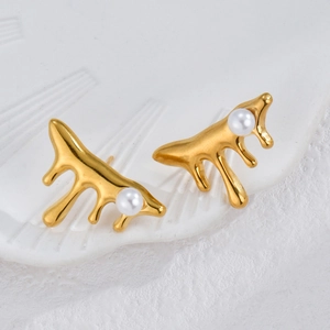 Irregular lava gold earrings with baroque pearls on a textured white ceramic plate