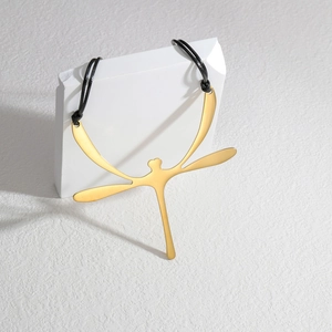 Detail of a golden dragonfly pendant necklace on minimalist white geometric stone props