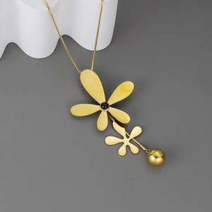 Artistic gold dragonfly necklace with black gemstone pendant on minimalist wave display