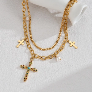 Dettaglio della collana a doppio strato dorata con croce di gemme e perle