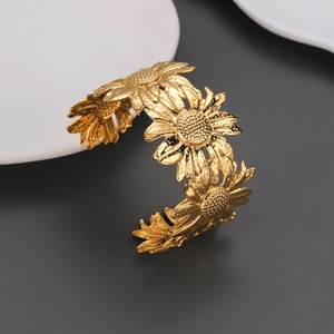 Makro-Detail des 18k vergoldeten Edelstahl-Armreifs mit floralem Sonnenblumen-Relief