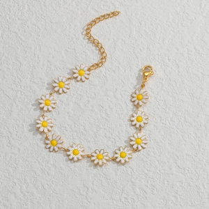 Detaillierte Nahaufnahme von goldenem Gänseblümchen-Armband mit weißen Emaille-Blütenblättern