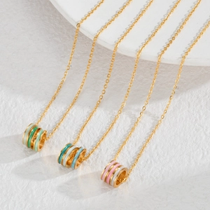 Macro detail of three-tone gold cylinder pendants with green, blue, and pink enamel bands