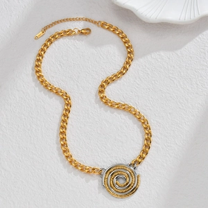 Macro d'une chaîne cubaine dorée et pendentif spirale bicolore sur surface texturée