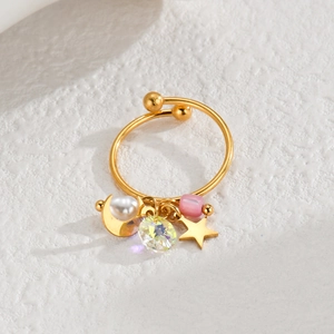 Macro detail of 18k gold plated open ring with pearl, crystal, and star charms