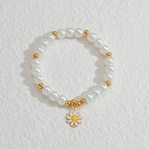 Detailansicht eines Gänseblümchen-Anhängers an einem Perlenarmband mit Goldakzenten