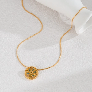 Collier arbre de vie plaqué or 18K avec pierres bleues sur fond blanc texturé chic