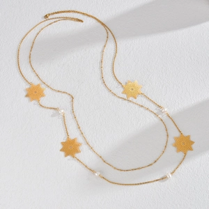 Collana lunga in acciaio al titanio dorato con stelle traforate e perle eleganti