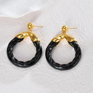 Boucles d'oreilles rondes rétro noires et métal doré sur fond de pierre blanche