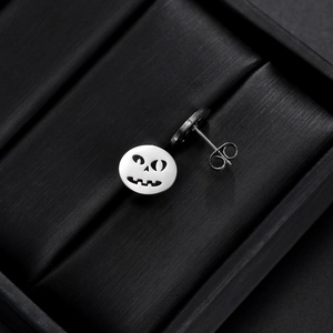 Macro view of stainless steel pumpkin skull earrings with butterfly back fasteners