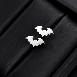 Detailed close-up of silver bat-shaped stud earrings on a black velvet display