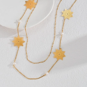 Collana lunga in acciaio al titanio con stelle dorate traforate e perle bianche