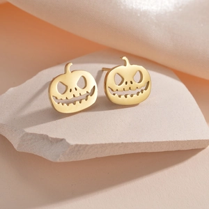 Golden pumpkin stud earrings with Halloween face design on a white textured stone