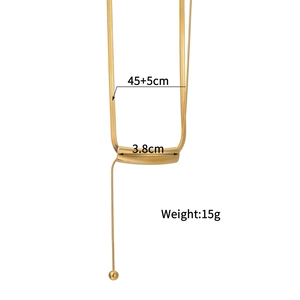 Gold snake chain necklace with a curved bar pendant and small metal sphere on a white background
