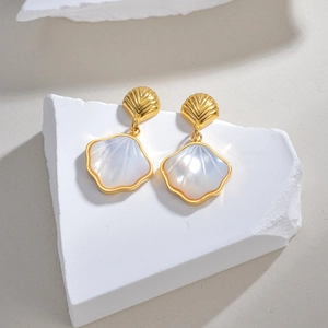 Détail de boucles d'oreilles en forme de coquille dorée avec nacre irisée