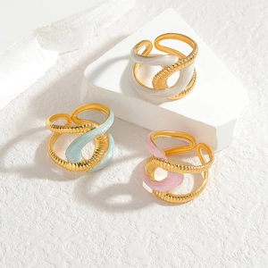 Three elegant twisted gold titanium rings with white, blue, and pink enamel accents