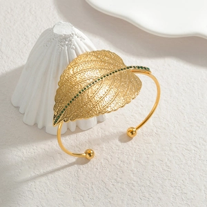 Minimalist gold leaf open bangle featuring hollow texture and green zircon accents