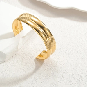 Bracelet jonc ouvert en acier inoxydable doré poli avec lignes parallèles et bords texturés