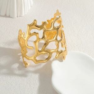 Wide gold irregular hollow cuff bracelet with organic textured design on a white pedestal